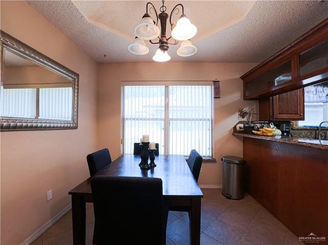 dining room with a wealth of natural light, tile patterned flooring, a textured ceiling, and a notable chandelier