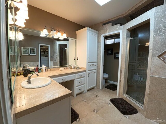 bathroom with tile patterned floors, vanity, a shower with shower door, and toilet