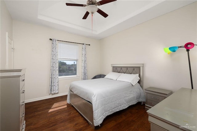 622 Comedy Ln, Edinburg, TX 78542 - bedroom featuring dark wood-style floors, a tray ceiling, baseboards, and a ceiling fan