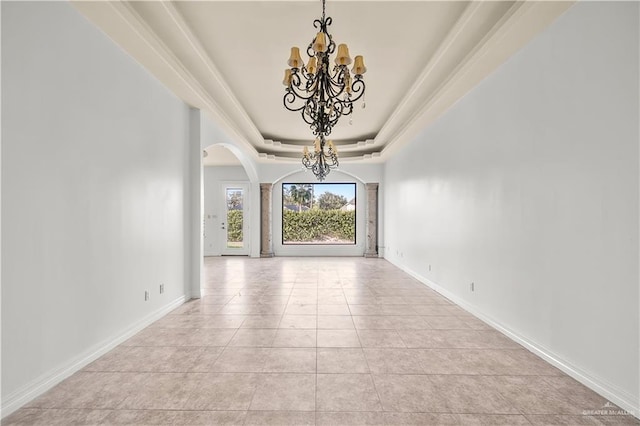 empty room featuring baseboards, a raised ceiling, arched walkways, and an inviting chandelier