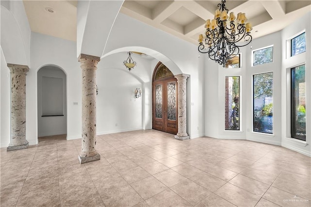 foyer featuring arched walkways, coffered ceiling, a towering ceiling, and ornate columns