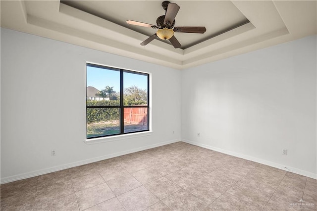 empty room featuring ceiling fan, baseboards, and a tray ceiling