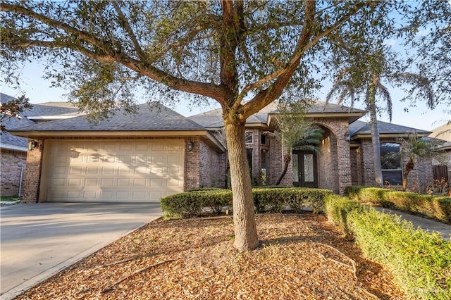 ranch-style house with french doors, driveway, brick siding, and an attached garage