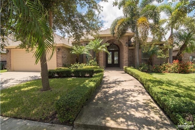 2913 San Rodrigo St, Mission, TX 78572 - view of front of house with a front yard, concrete driveway, french doors, and brick siding