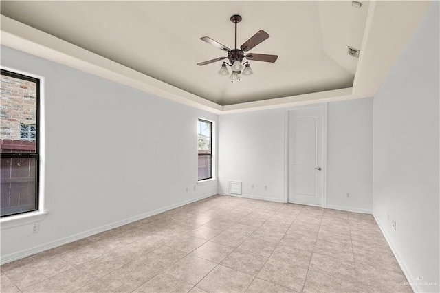 unfurnished room with visible vents, baseboards, light tile patterned floors, a raised ceiling, and a ceiling fan