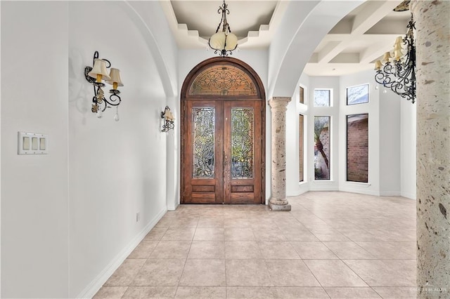 foyer featuring light tile patterned floors, french doors, coffered ceiling, and a high ceiling