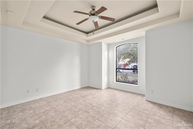 unfurnished room featuring baseboards, a raised ceiling, ceiling fan, and light tile patterned flooring