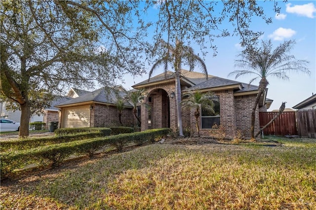 view of front facade featuring brick siding, an attached garage, a front lawn, and fence