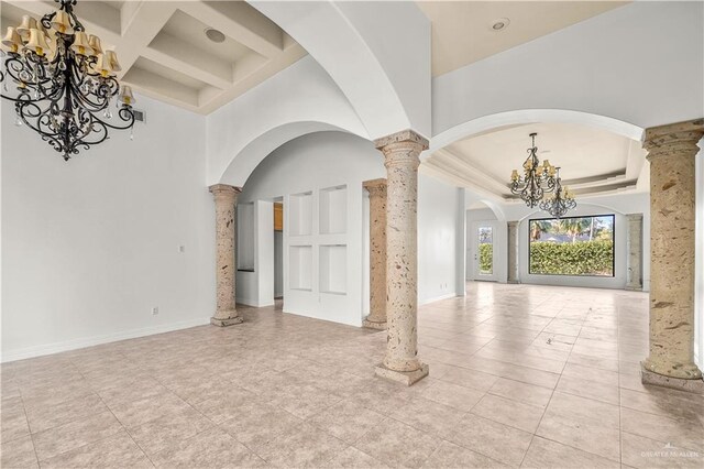 interior space with beam ceiling, a high ceiling, an inviting chandelier, coffered ceiling, and ornate columns