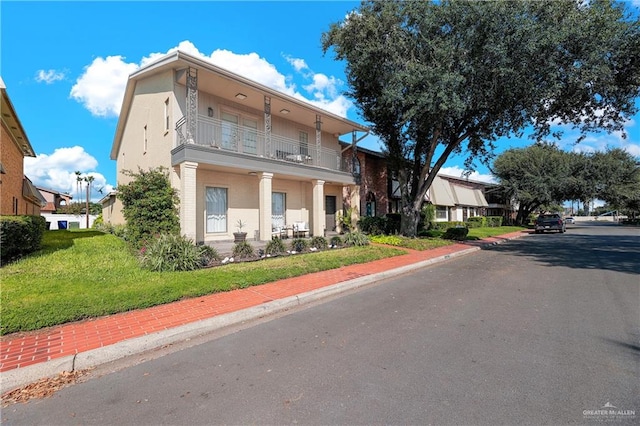 view of front of home with a balcony and a front lawn