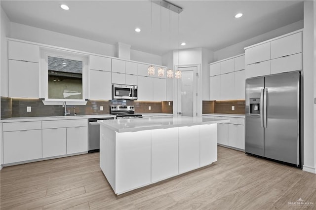 kitchen with stainless steel appliances, white cabinetry, a sink, and modern cabinets