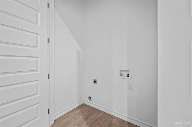 clothes washing area featuring hookup for a washing machine, hookup for an electric dryer, wood finished floors, laundry area, and baseboards