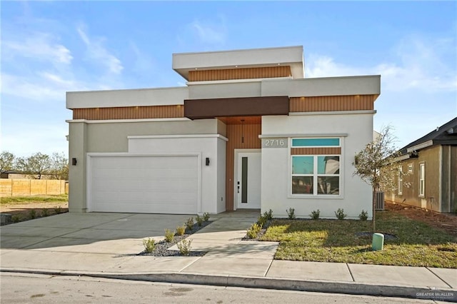 contemporary home featuring concrete driveway, an attached garage, and stucco siding