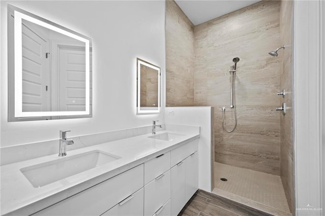 bathroom featuring a tile shower, double vanity, and a sink