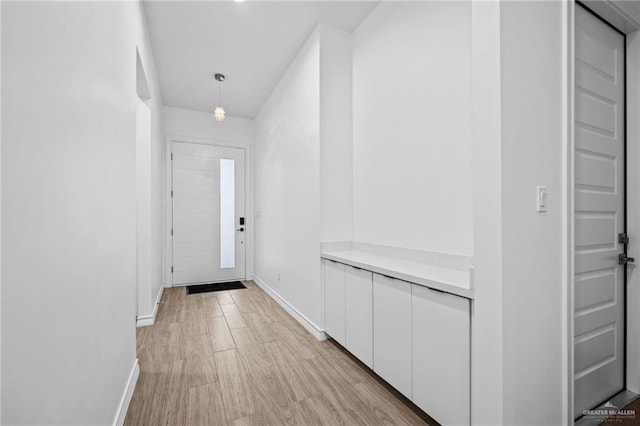 doorway to outside with light wood-style flooring and baseboards