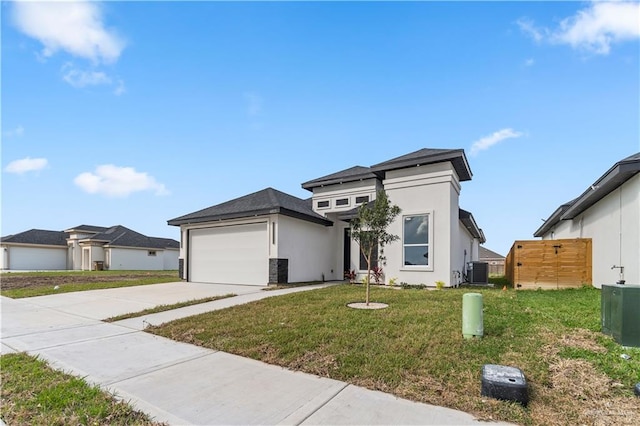 prairie-style home featuring central AC unit, a garage, and a front lawn