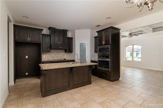 kitchen featuring a center island with sink, ceiling fan with notable chandelier, sink, decorative backsplash, and stainless steel appliances