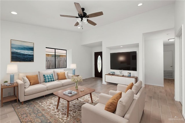 living room with lofted ceiling, light hardwood / wood-style flooring, and ceiling fan