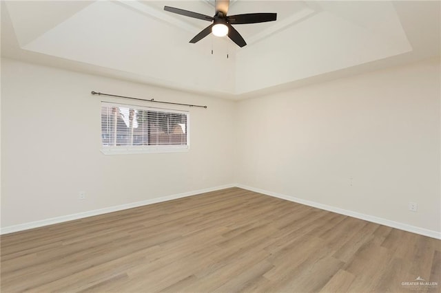 spare room with ceiling fan, a tray ceiling, and light hardwood / wood-style floors