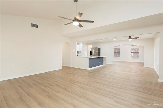 unfurnished living room with ceiling fan, lofted ceiling, and light hardwood / wood-style floors