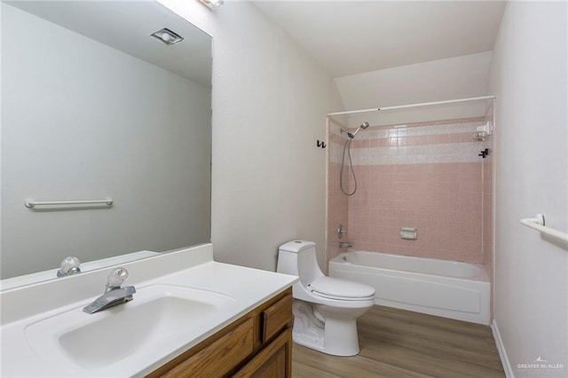 full bathroom featuring tiled shower / bath, vanity, toilet, and hardwood / wood-style floors