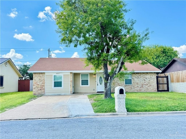 ranch-style house with a front yard, brick siding, and fence