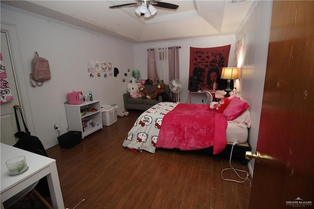 bedroom featuring ceiling fan, dark hardwood / wood-style flooring, and a tray ceiling