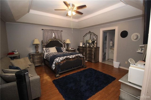 bedroom featuring ceiling fan, dark wood-type flooring, ensuite bath, and a raised ceiling