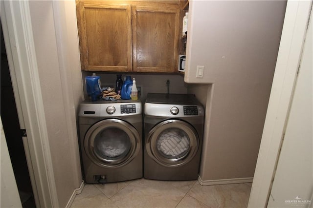 washroom with light tile patterned floors, cabinets, and washer and dryer