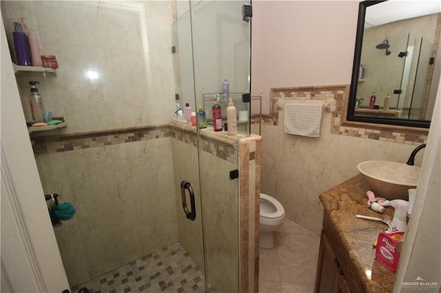 bathroom featuring toilet, vanity, tile walls, and a shower with door