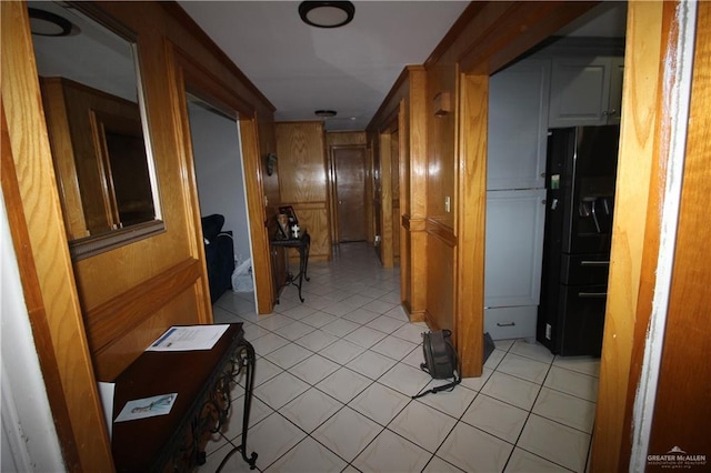 corridor with light tile patterned floors and wooden walls