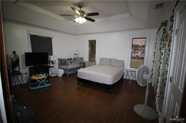 bedroom featuring ceiling fan, dark hardwood / wood-style floors, and a raised ceiling