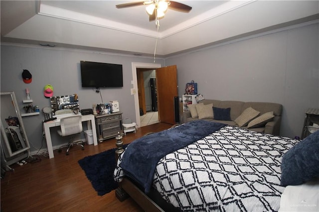 bedroom with ceiling fan, a tray ceiling, and dark hardwood / wood-style flooring