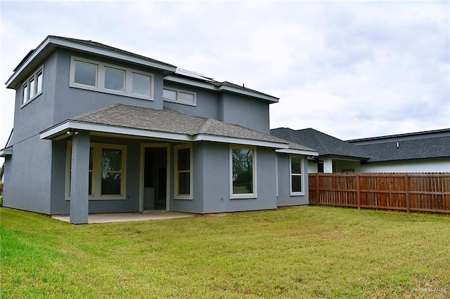 rear view of property featuring stucco siding, a patio area, fence, and a lawn