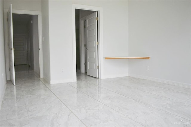 spare room featuring marble finish floor and baseboards