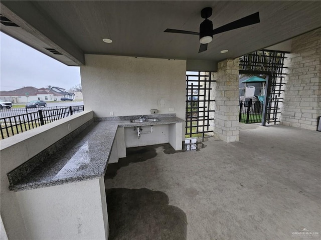 view of patio with a sink, fence, an outdoor kitchen, and ceiling fan