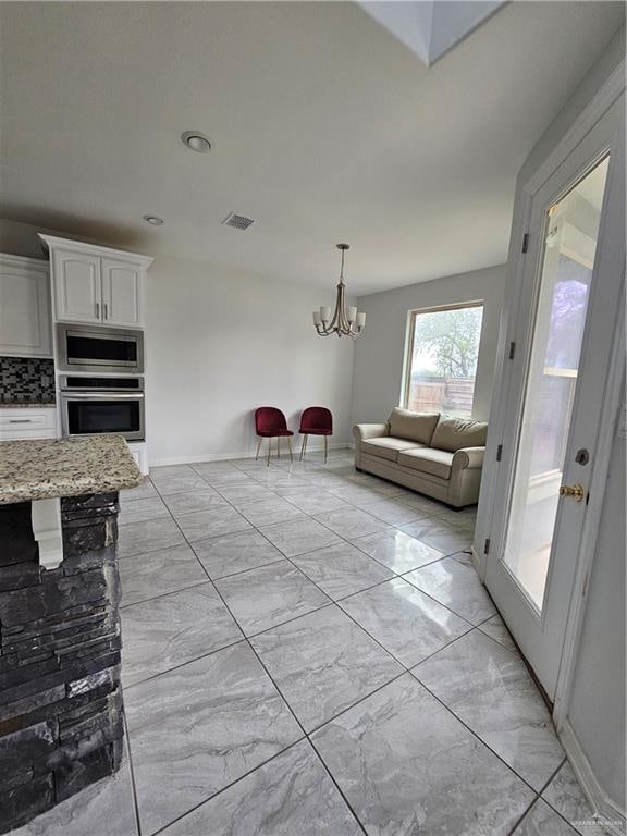 interior space featuring a notable chandelier, marble finish floor, visible vents, and baseboards