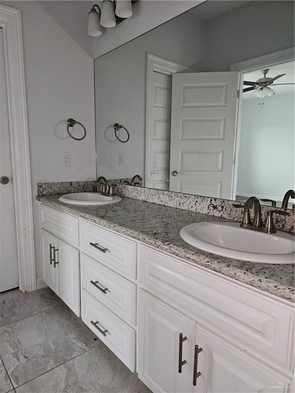 full bathroom featuring ceiling fan, marble finish floor, a sink, and double vanity