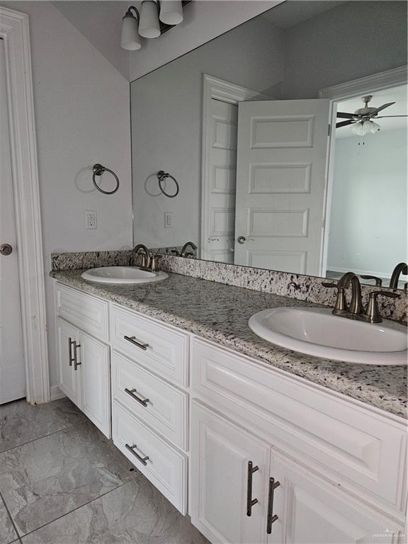 bathroom featuring double vanity, marble finish floor, ceiling fan, and a sink