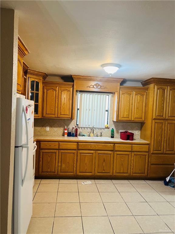 kitchen featuring decorative backsplash, white fridge, light tile patterned floors, and sink