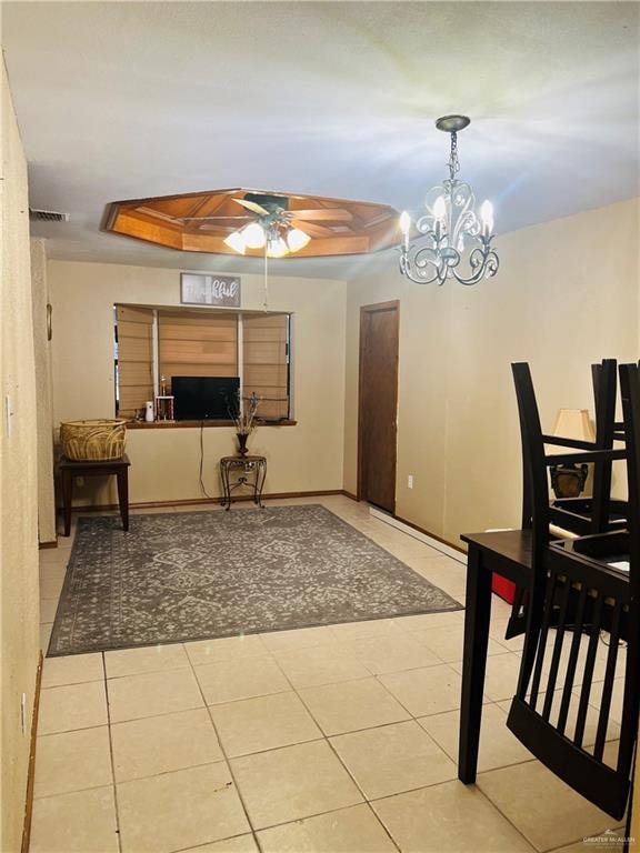 dining area featuring light tile patterned floors, ceiling fan with notable chandelier, and a tray ceiling