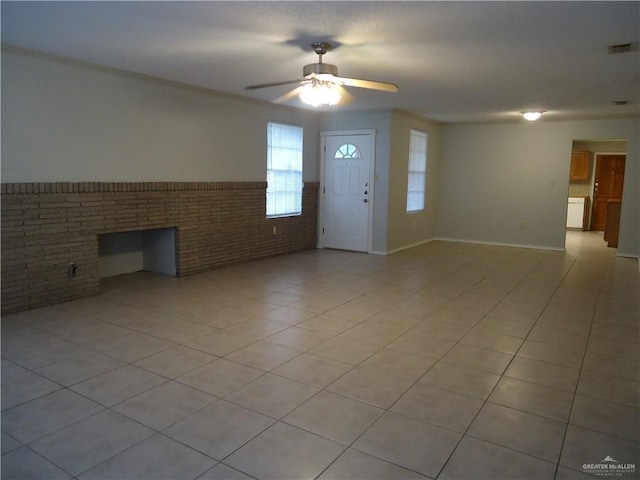 interior space with ceiling fan, a fireplace, light tile patterned floors, and brick wall