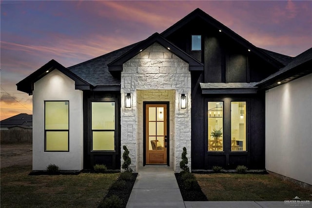 view of front of property featuring stone siding, roof with shingles, and stucco siding