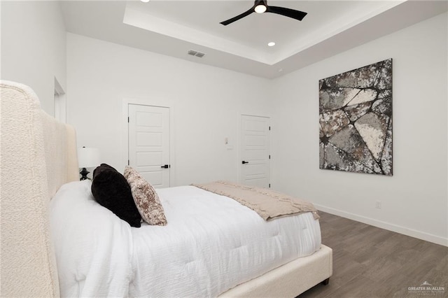 bedroom featuring baseboards, visible vents, a raised ceiling, dark wood-type flooring, and recessed lighting