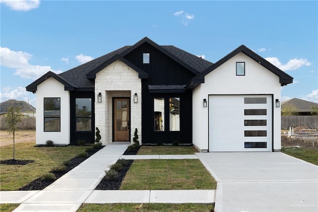 view of front of property featuring an attached garage, concrete driveway, stone siding, roof with shingles, and a front lawn