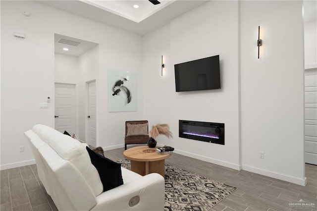 living area featuring visible vents, baseboards, a glass covered fireplace, wood tiled floor, and recessed lighting