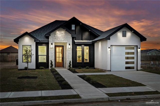 view of front of house with an attached garage, fence, stone siding, driveway, and a lawn