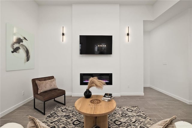 living room featuring baseboards, a glass covered fireplace, and wood tiled floor