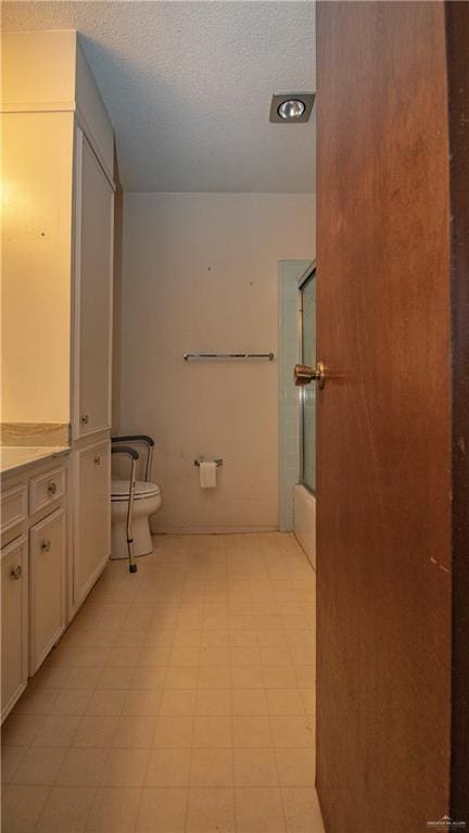 300 W Westway Ave, Mcallen, TX 78501 - full bathroom featuring tile patterned floors, toilet, vanity, bath / shower combo with glass door, and a textured ceiling