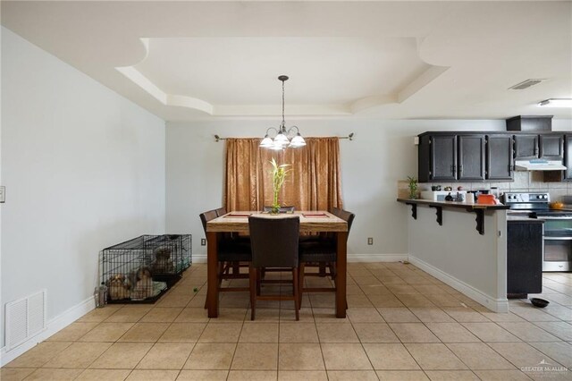 tiled dining space featuring a chandelier and a raised ceiling